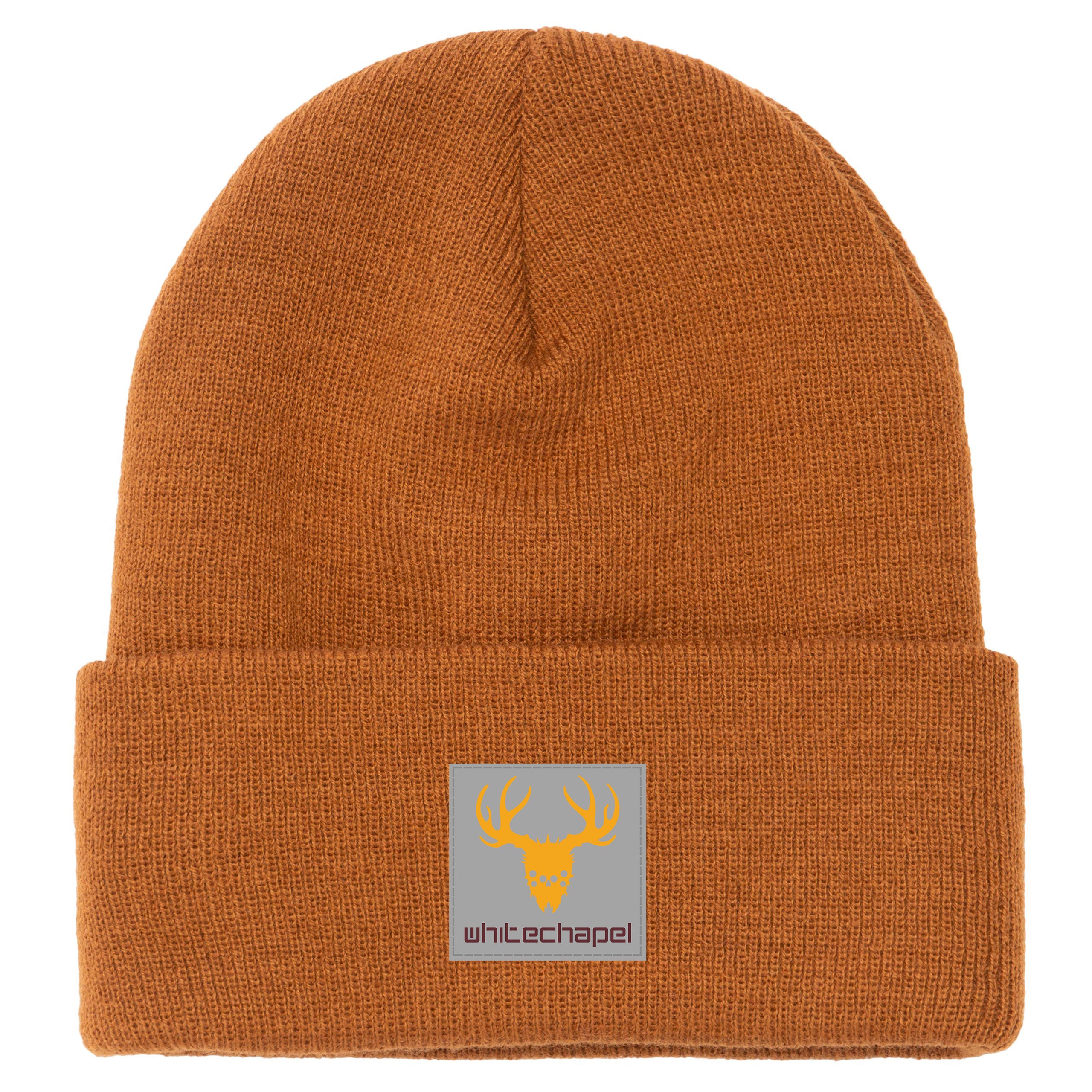 The Whitechapel brown knit beanie features a folded brim and a gray front patch with a yellow deer skull and antlers above 