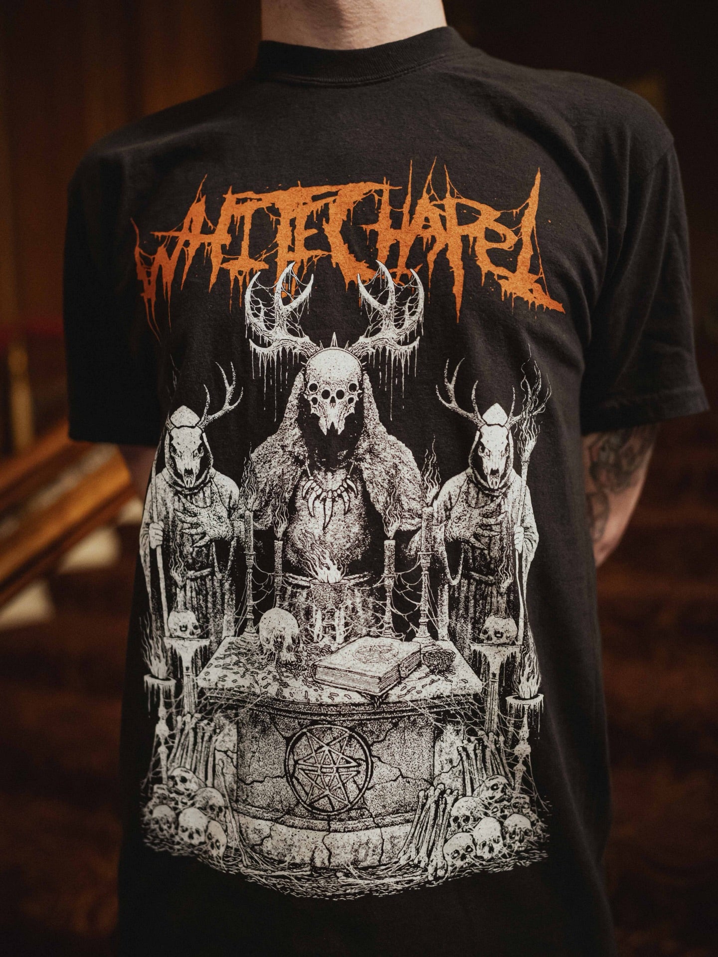 A person wearing a Whitechapel black ring-spun cotton T-shirt with jagged orange 