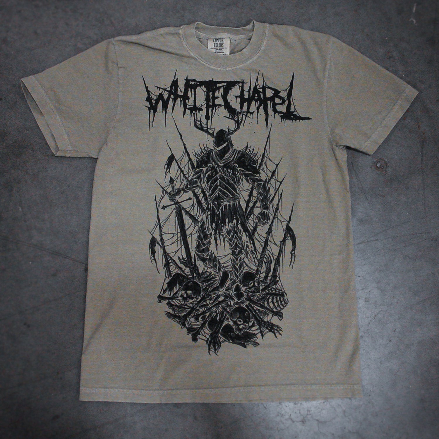 A gray Comfort Colors T-shirt by Whitechapel is garment-dyed and displays a black, jagged Whitechapel logo with detailed art of a skeletal grim reaper surrounded by skulls and bones on the front.