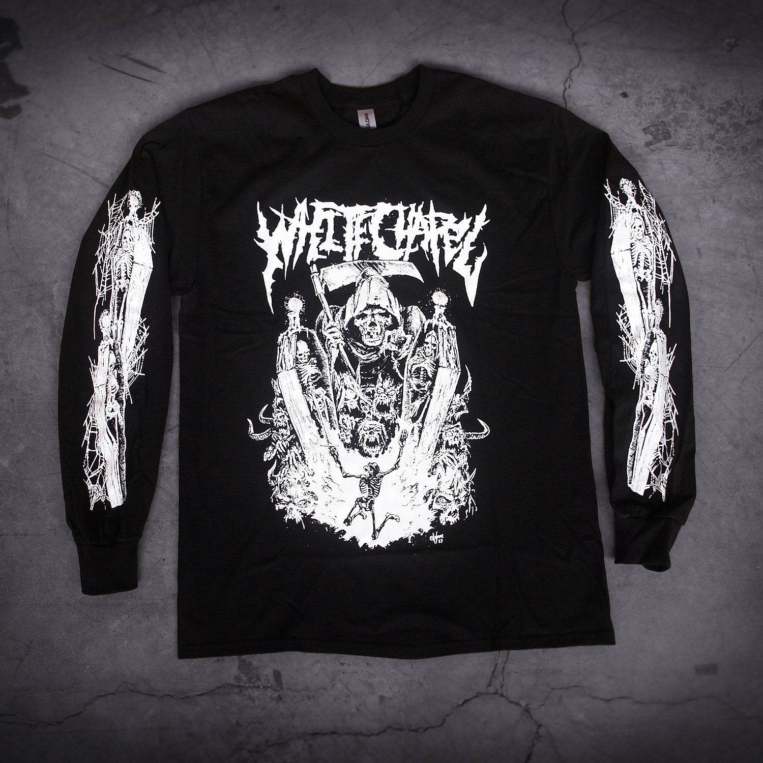 image of a black long sleeve tee shirt laid on a concrete floor. front has full body print in white of a grim reaper looking over a skeleton. at the top says whitechapel. each sleeve has prints of skeletons in coffins