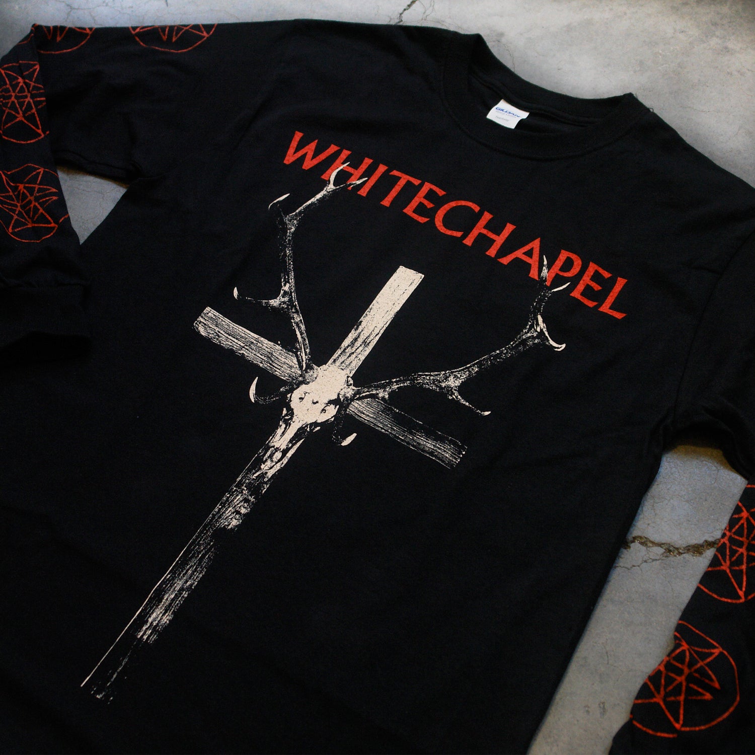 close up Image of a black longsleeve against a grey concrete background. Across the chest in red text reads 