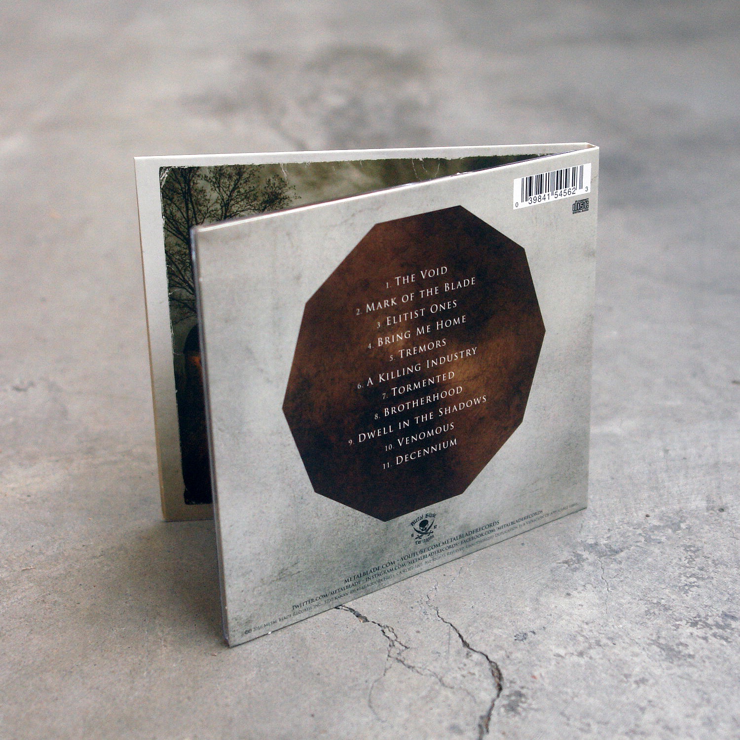 image of the back of a CD on a concrete floor. The back side shows the tracklist